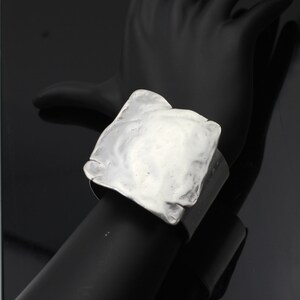 Op de afbeelding: Een zilveren vierkante armband met een getextureerd oppervlak.