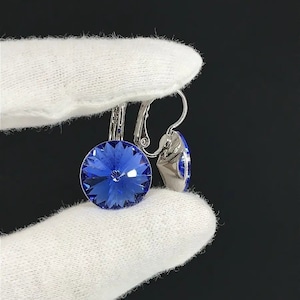 May include: A pair of silver earrings with a blue crystal stone. The earrings have a clip-on fastening.