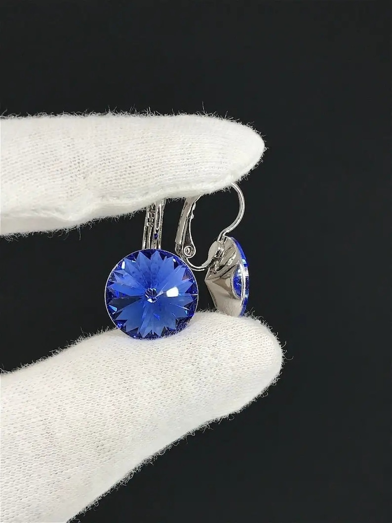 May include: A pair of silver earrings with a blue crystal stone. The earrings have a clip-on fastening.