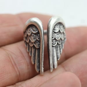 May include: A silver ring with a detailed design of angel wings.