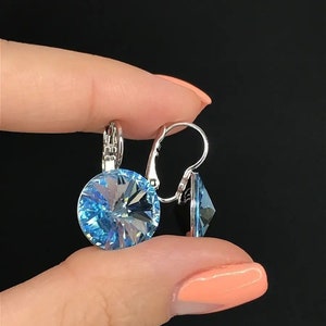 May include: A pair of silver earrings with light blue crystal stones. The earrings have a simple design and are perfect for everyday wear.