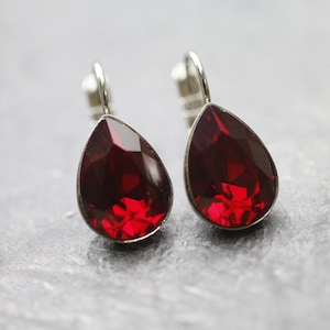 Puede incluir: Un par de pendientes de plata en forma de lágrima con piedras de cristal rojas.