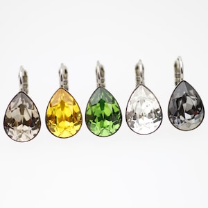 Puede incluir: Cinco pendientes en forma de lágrima con engastes plateados. Los pendientes son de color gris, amarillo, verde, transparente y negro.