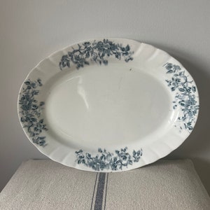 May include: A white oval serving platter with a blue floral design around the edge.