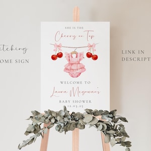 Puede incluir: Un cartel de bienvenida blanco con el texto "She is the Cherry on Top" en letra cursiva negra. El cartel tambi&eacute;n incluye un body de beb&eacute; rosa con una cereza en la parte superior, y el texto "Welcome to Laura McGowan's Baby Shower 12.03.25" en negro.