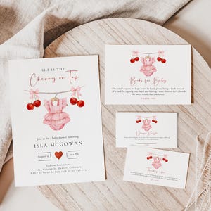 Puede incluir: Invitaci&oacute;n a un baby shower rosa y rojo con un tema de cereza. La invitaci&oacute;n dice "Ella es la cereza del pastel" y presenta un mameluco rosa para beb&eacute; con cerezas colgando de una cuerda. La invitaci&oacute;n tambi&eacute;n incluye el nombre del beb&eacute;, Isla McGowan, y la fecha y hora del baby shower.