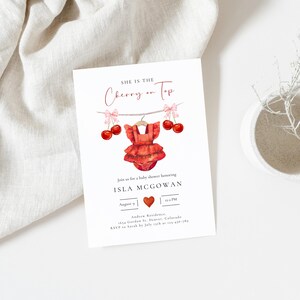 May include: A baby shower invitation with the text "She is the Cherry on Top." The invitation features a watercolor illustration of a red baby romper hanging on a clothesline with cherries. The invitation includes the name Isla McGowan and event details.