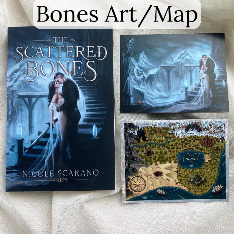 Pu&ograve; includere: Un libro intitolato "The Scattered Bones" con un'illustrazione di copertina di una coppia che si abbraccia su una scala. Accanto, due stampe artistiche: una di una coppia e un'altra di una mappa con una rosa dei venti.