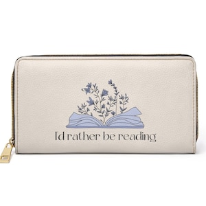 May include: A cream-colored zippered wallet with a book and flowers design. The text "I'd rather be reading" is printed on the front.