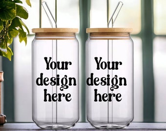 May include: Two clear glass tumblers with bamboo lids and straws. The tumblers have the text "Your design here" printed on them.