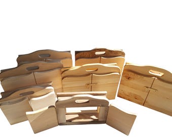 May include: A collection of unfinished wooden serving trays with handles. The trays are rectangular with a wavy top edge and a handle cut into the wood. Some trays have hinged doors. The wood has a light, natural color.