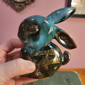以下が含まれることがあります： バーリントンカナダと金色の文字で書かれた、ターコイズブルーのセラミック製のウサギの置物です。