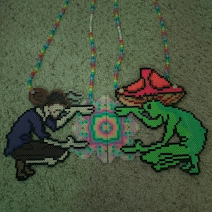 May include: A beaded necklace with a colorful mandala design in the center. On one side is a purple figure with a hat and on the other side is a green figure with a red mushroom.