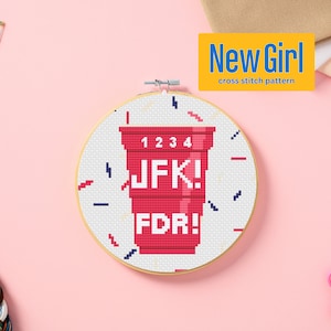 Könnte beinhalten: Ein roter Plastikbecher mit den Zahlen 1, 2, 3, 4 auf der Oberseite und den Worten "JFK!" und "FDR!" auf den Seiten. Der Becher befindet sich auf einem weißen Hintergrund mit einem blauen und roten Konfetti-Muster.