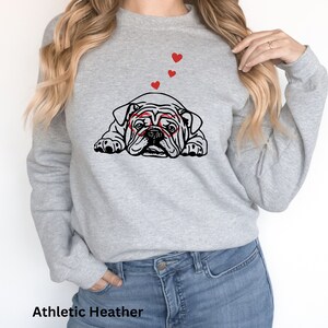 May include: A gray sweatshirt with a black and white illustration of a bulldog wearing heart-shaped glasses. There are three red hearts above the bulldog.