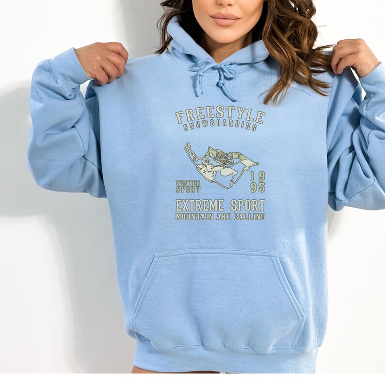 May include: Light blue hoodie with a graphic print of a snowboarder and the text "FREESTYLE SNOWBOARDING WINTER SPORT 1995 EXTREME SPORT MOUNTAIN ARE CALLING".