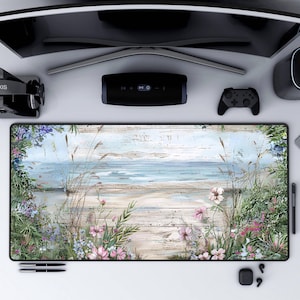 May include: A beach-themed mousepad with a light blue ocean, white sand, and weathered wood planks. Pink and white flowers and green grass are in the foreground.