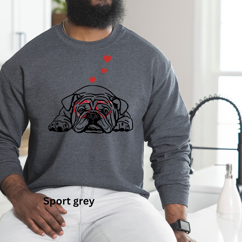 May include: A dark grey sweatshirt with a black and white illustration of a bulldog wearing heart-shaped glasses. Three red hearts are above the bulldog. The text "Sport grey" is visible at the bottom of the image.
