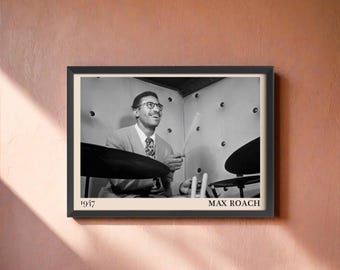May include: Framed monochrome print of a drummer playing his kit. The print includes the text "1947" and "MAX ROACH". The man is wearing glasses and a tie. The image is set against a neutral background.