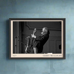 May include: Black and white photograph of Gerry Mulligan playing a saxophone. The photo is framed in a black frame with a white mount. The photo is dated 1972 and the name Gerry Mulligan is printed below the photo.