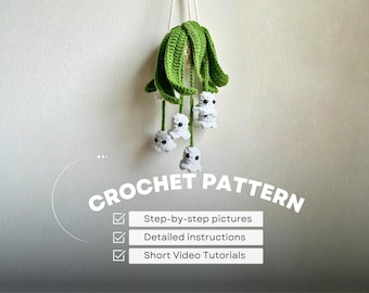 May include: A handmade crochet pattern for a hanging mobile. The mobile features a green, leafy top with white ghost-like figures hanging below. The text "CROCHET PATTERN" is displayed with checkmarks indicating step-by-step pictures, detailed instructions, and short video tutorials.