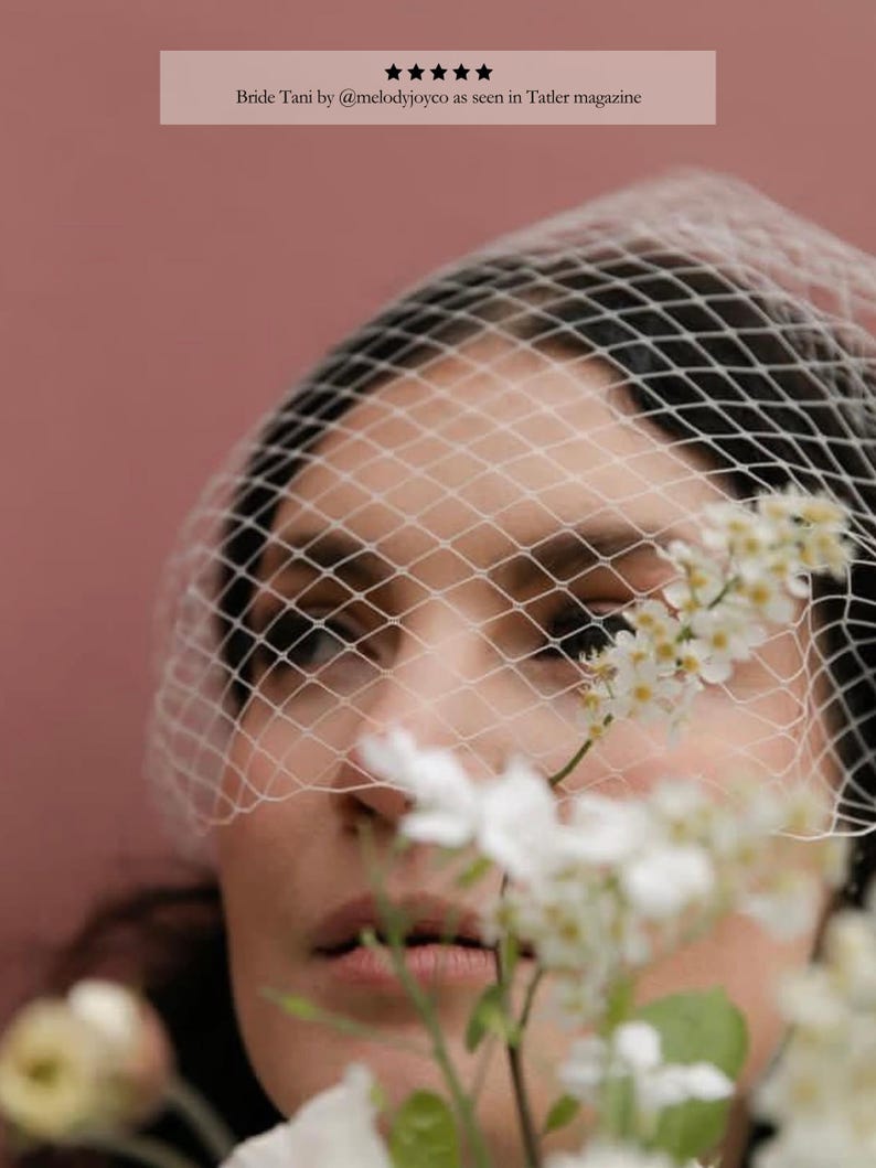 May include: A close-up of a person wearing a white net veil. White flowers are in the foreground, with a pink background. Text at the top reads "Bride Tani by @melodyjoyco as seen in Tatler magazine."