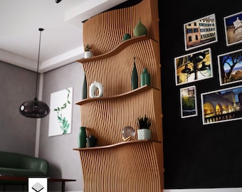 Puede incluir: Una estantería de pared de madera con un diseño ondulado. La estantería tiene cuatro estantes y está decorada con plantas, jarrones y otros elementos decorativos. La pared es negra y la estantería está hecha de madera clara.