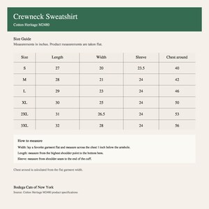 May include: A size guide chart for a Cotton Heritage M2480 crewneck sweatshirt. The table lists sizes from S to 3XL with corresponding length, width, sleeve, and chest measurements in inches. Includes instructions on how to measure the garment flat.
