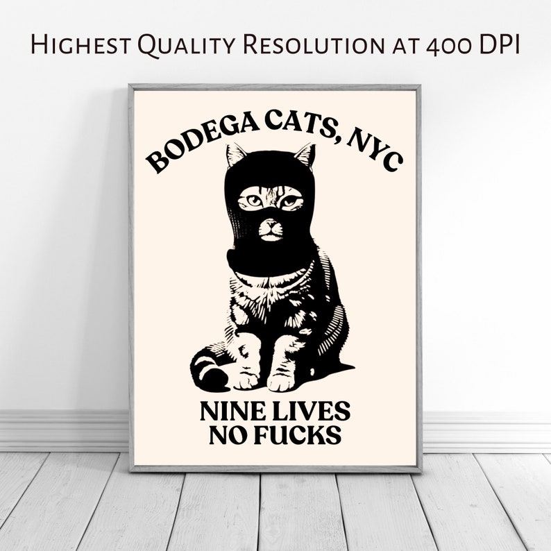 May include: A black and white illustration of a cat wearing a black ski mask. The cat is sitting with its paws crossed. The text "Bodega Cats, NYC" is above the cat and the text "Nine Lives No Fucks" is below the cat.