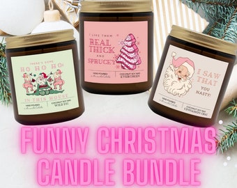 May include: A 3-pack bundle of Christmas-themed candles with funny sayings. The candles are in brown glass jars with gold lids. The labels are pink with white text. The candles are labeled "There's some Ho Ho Hos in this house", "I like them real thick and sprucey", and "I saw that you nasty!"