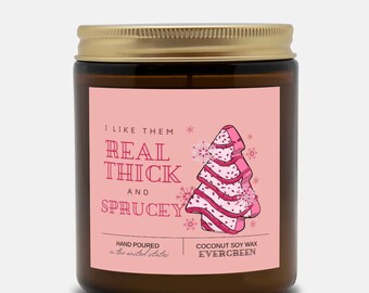May include: A pink candle with a gold lid and a pink label that says "I like them real thick and sprucey". The label also features a pink and white Christmas tree illustration and the text "Coconut Soy Wax Evergreen".