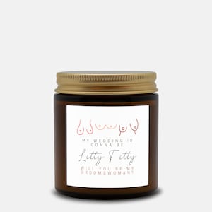 May include: A brown glass jar with a gold lid. The label features a line drawing of breasts and the text "MY WEDDING IS GONNA BE Litty Titty WILL YOU BE MY GROOMSWOMAN?"