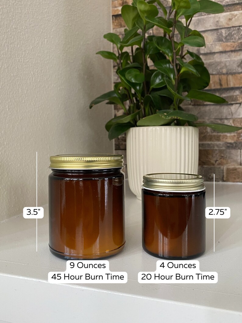 May include: Two amber glass candle jars with gold lids. The larger jar is 3.5 inches tall and holds 9 ounces of candle wax. The smaller jar is 2.75 inches tall and holds 4 ounces of candle wax. The larger jar has a burn time of 45 hours and the smaller jar has a burn time of 20 hours.