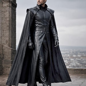 May include: A black leather long coat with a high collar, structured shoulders, and a matching belt at the waist. The coat features a full-length cape attached to the shoulders, paired with black leather gloves, slim-fit trousers, and black boots.