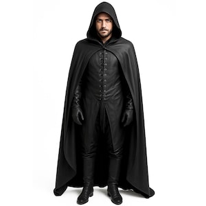 May include: A black hooded cloak and matching outfit. The cloak has a long, flowing design with a hood. The outfit includes a long-sleeved shirt with a lace-up front, pants, gloves, and boots. The outfit is made of a dark, possibly leather-like material.