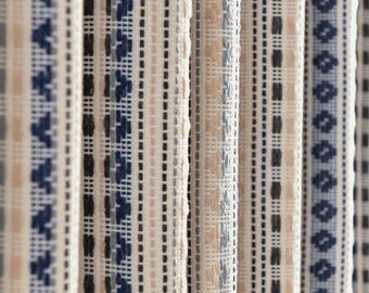 May include: Close-up of woven fabric with vertical stripes. The stripes feature a repeating pattern of white, navy blue, black, and beige. The fabric has a textured appearance, suggesting a natural fiber material.