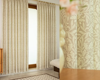 May include: A pair of beige curtains with a white floral pattern. The curtains are hung on a gold rod and are drawn back to reveal a window with a view of a tiled floor.
