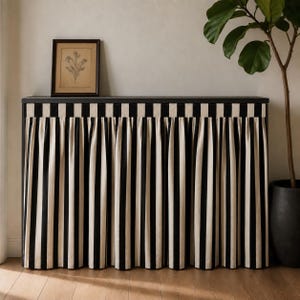 May include: A rectangular console table featuring a black top and a pleated fabric skirt with vertical black and cream stripes. The skirt covers the front and sides of the table, creating a uniform appearance with consistent vertical lines.