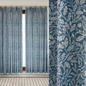 May include: Two blue and white patterned curtains with a floral design hang in a window. The curtains are made of a soft, woven fabric and have a subtle sheen.