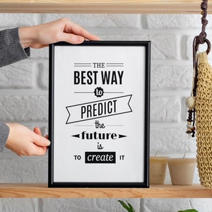Könnte beinhalten: Schwarzweißes Motivationszitat in einem schwarzen Rahmen an einer weißen Backsteinwand. Das Zitat lautet: "Der beste Weg, die Zukunft vorherzusagen, ist, sie zu erschaffen."