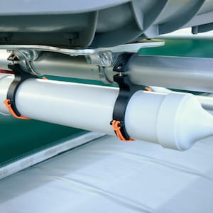 May include: A white cylindrical boat accessory with a black tip, secured by black and orange clamps to a silver bar. The accessory is mounted on a green and white boat structure.
