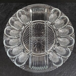 May include: A clear glass serving dish with six individual compartments and a center divider. The dish has a decorative, diamond-shaped pattern.