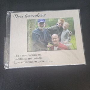 May include: A framed photograph featuring three generations of a family. The frame is light-colored with the words "Three Generations" at the top. The text "The name carries on traditions are passed Love continues to grow..." is printed below the photo.