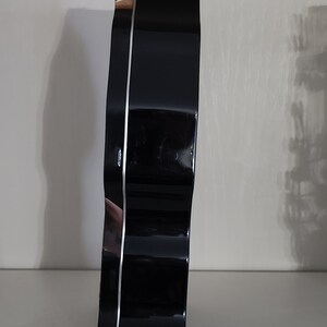 Puede incluir: Una lata de galletas de metal negro con un dise&ntilde;o de borde ondulado. La lata tiene un borde plateado.