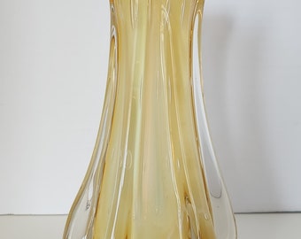 May include: A clear glass vase with a yellow amber tint and a wavy, textured design. The vase has a wide mouth and a narrow base.
