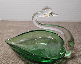 May include: A green glass swan shaped dish with a clear glass head and neck.