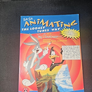 May include: A book titled "Animating the Looney Tunes Way" featuring Bugs Bunny and Daffy Duck. The cover has a red and blue background with the Looney Tunes logo. The book includes character model sheets.