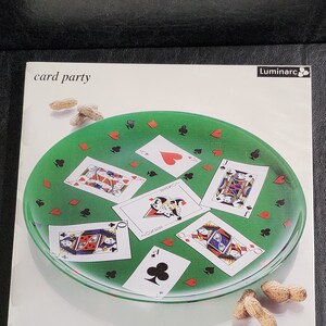 May include: A green glass serving platter with a card party theme. The platter is decorated with playing cards and peanuts. The platter is 12 1/2 inches in diameter.