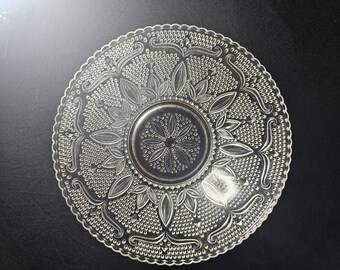 May include: A clear glass plate with a decorative pattern of leaves and dots. The plate has a raised edge and a center well.