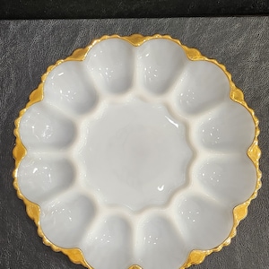 May include: White egg plate with a gold rim. The plate has 12 individual compartments for eggs.